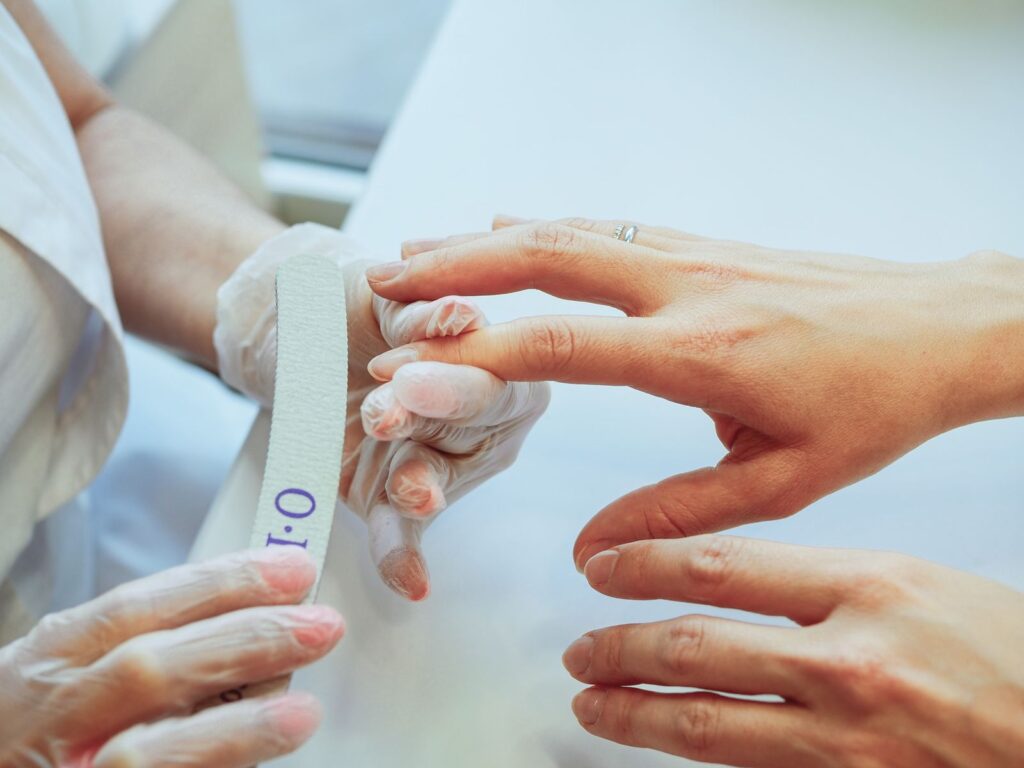 Manicurist shaping a client's nails with a file