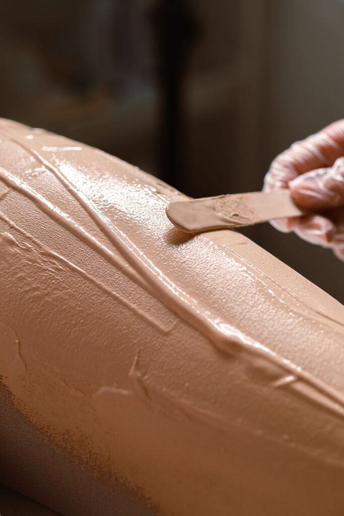 Wax being spread on the skin with a wooden spatula