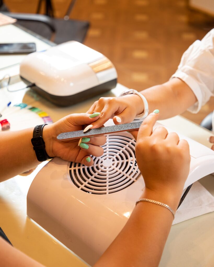 Nail technician filing a client's nails during a manicure