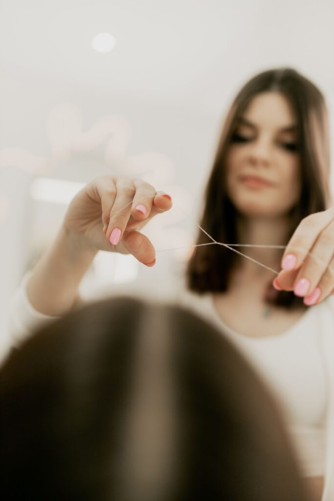 Beautician threading a client's eyebrows in a salon