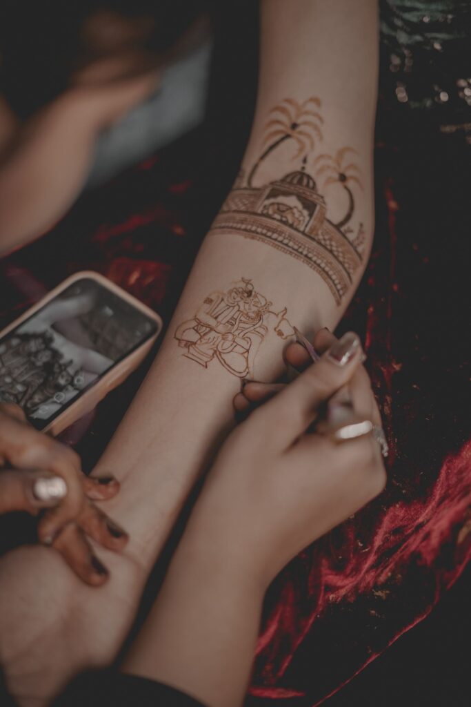 Mehndi artist applying a bridal design to a client's arm